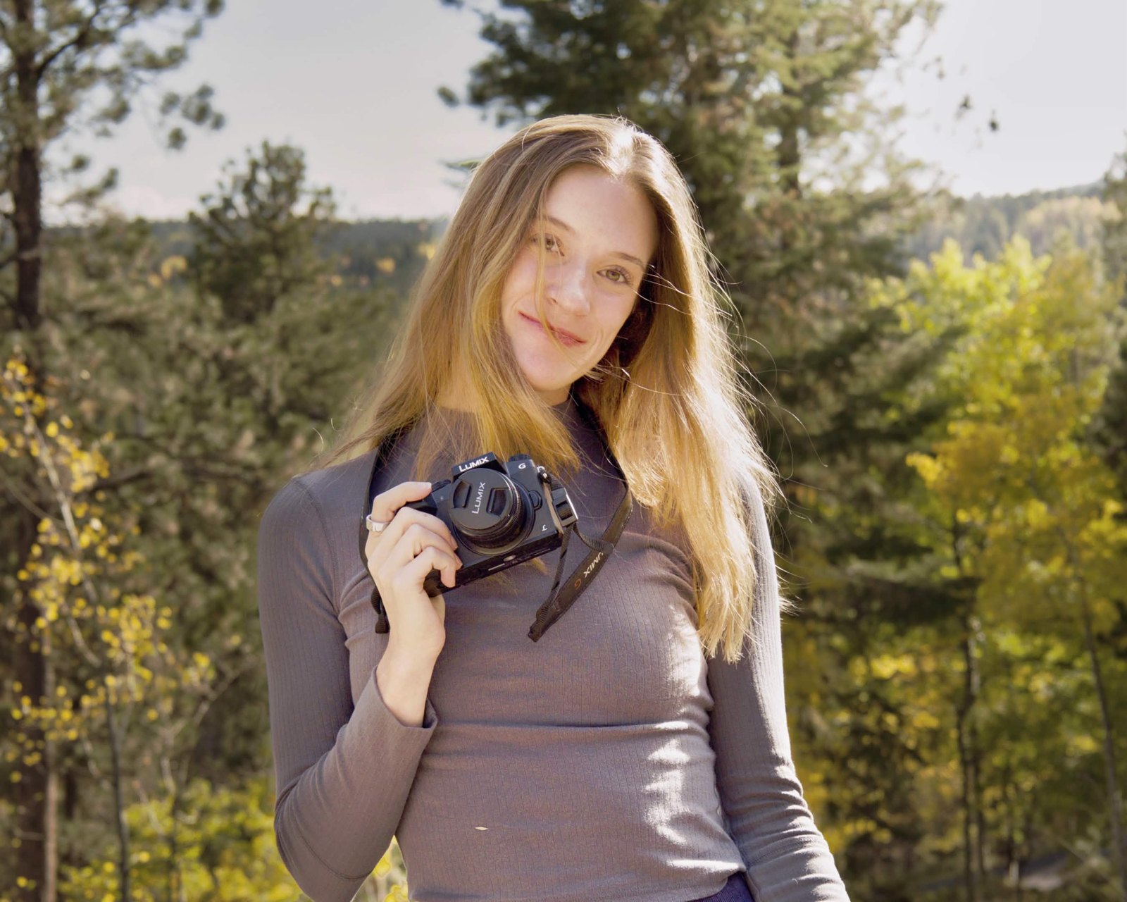 Jen, a Colorado photographer, holding her camera in the trees