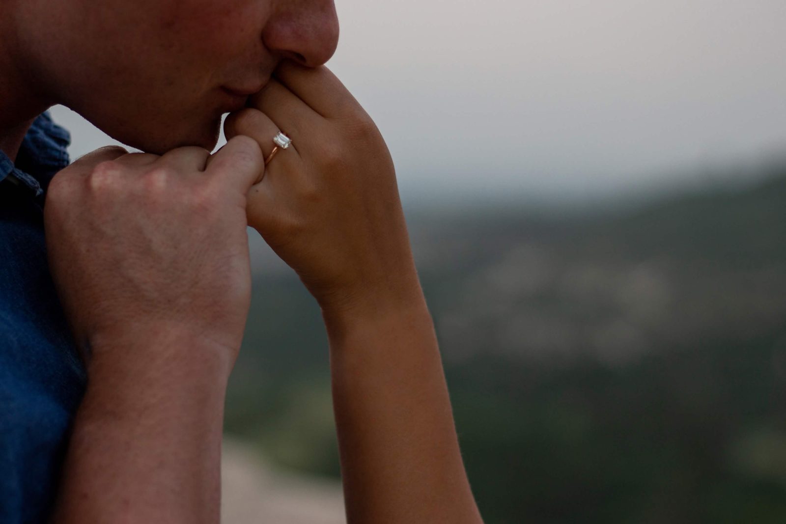 He kisses her hand and engagement ring at Phillip S. Miller Park in Castle Rock