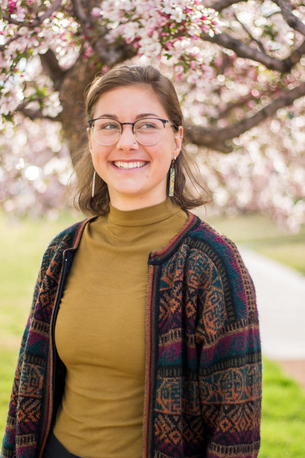 College senior smiling under a blossoming tree at Colorado College in Colorado Springs