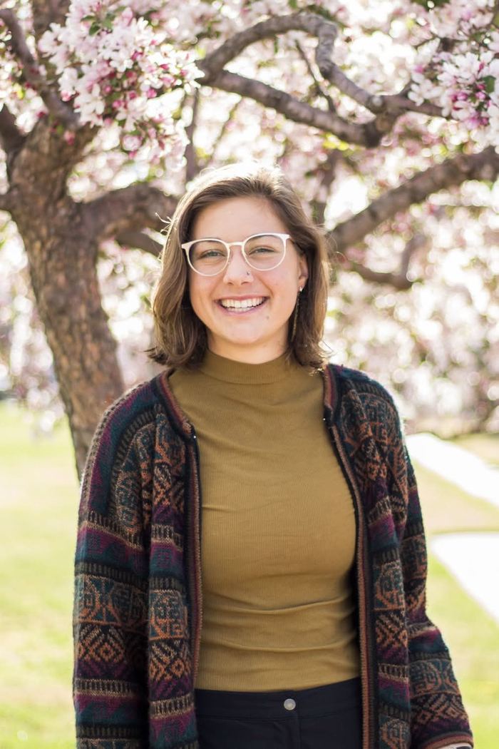 Spring senior portrait in front of pink blossoms on the Colorado College campus