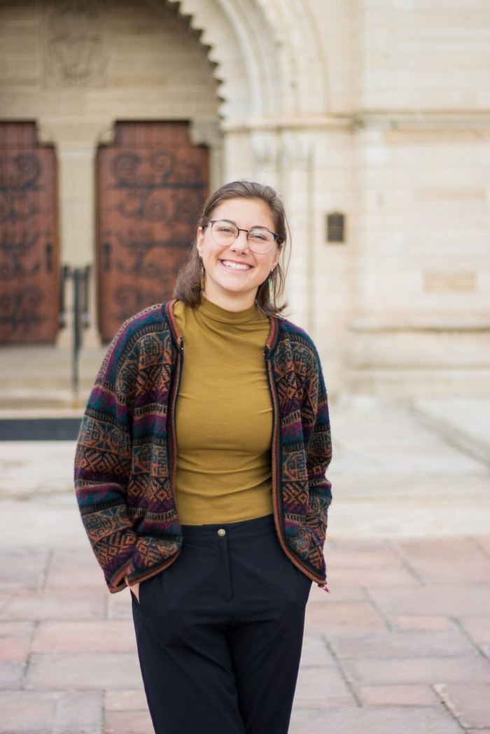Senior standing in front of the historic stone doors on the Colorado College campus