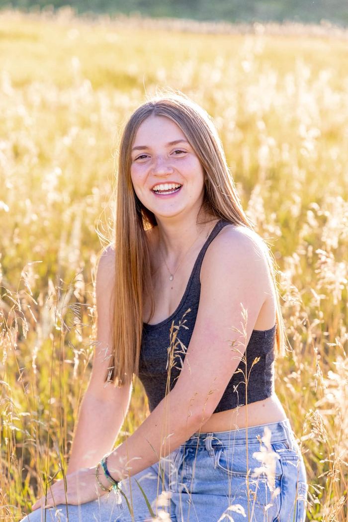 Relaxed senior portrait sitting in the golden meadow