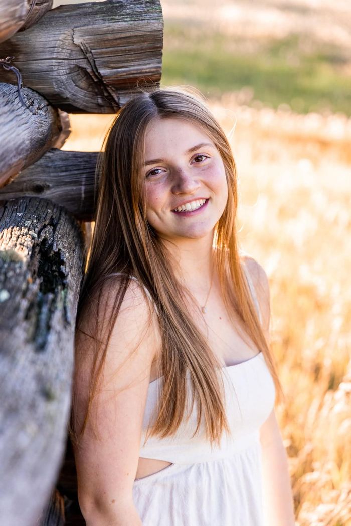 Senior portrait against an old wooden structure at Elk Meadow in Evergreen