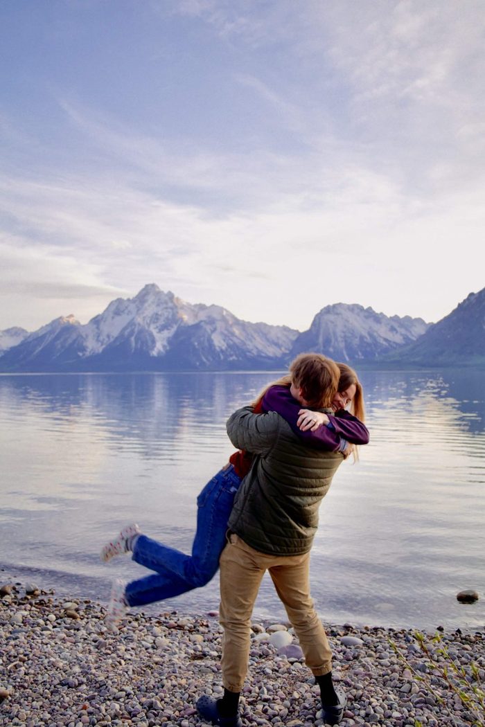 She jumps into his arms for a hug on the lakeshore in Grand Teton National Park