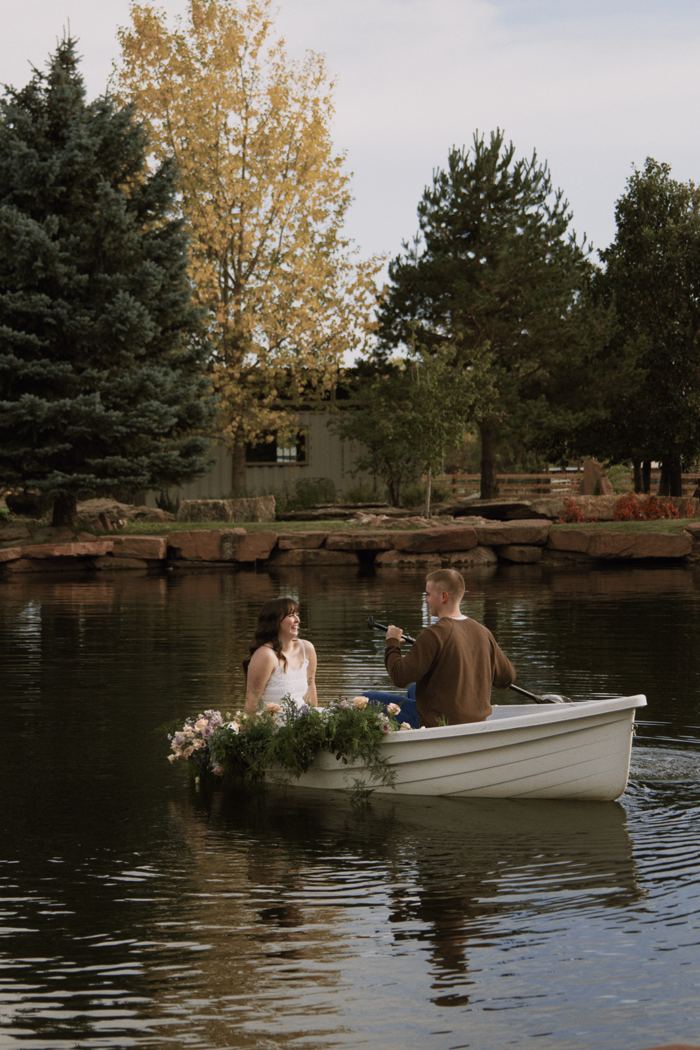 Couple in a flower-covered rowboat on the pond at Lazy Stud Ranch