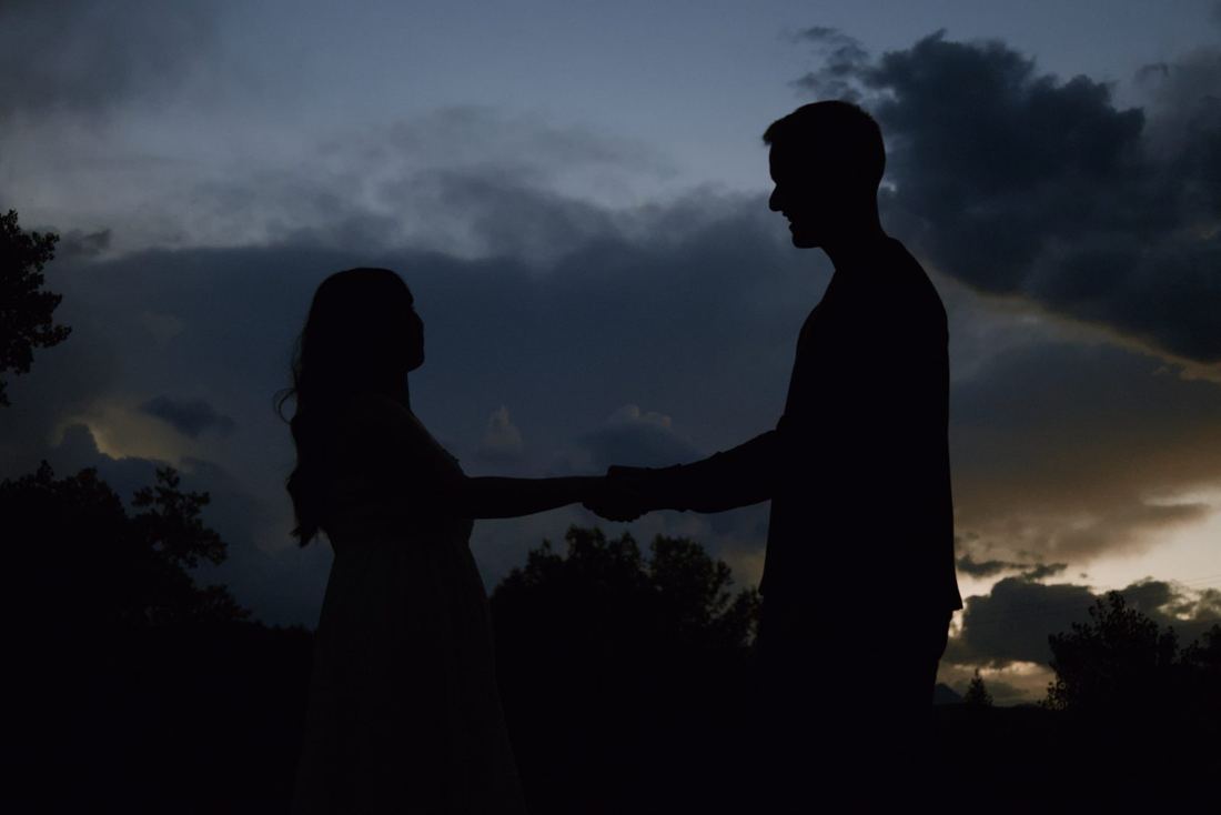 Silhouette of the couple holding hands against the deep blue evening sky
