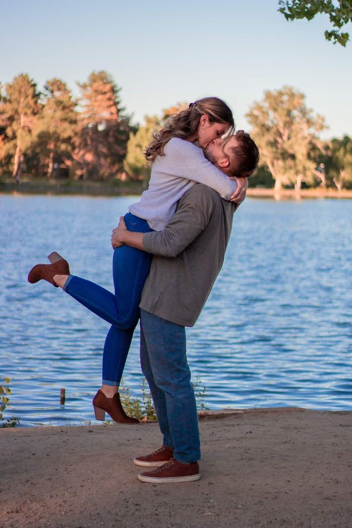 He lifts her up for a kiss on the shore of the lake at Washington Park, Denver