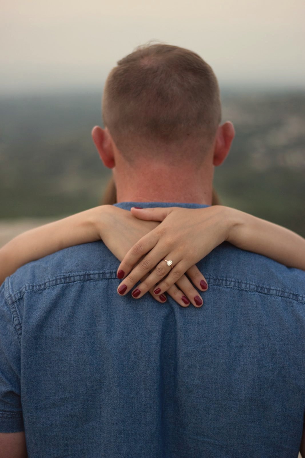Ring detail, hands on shoulders