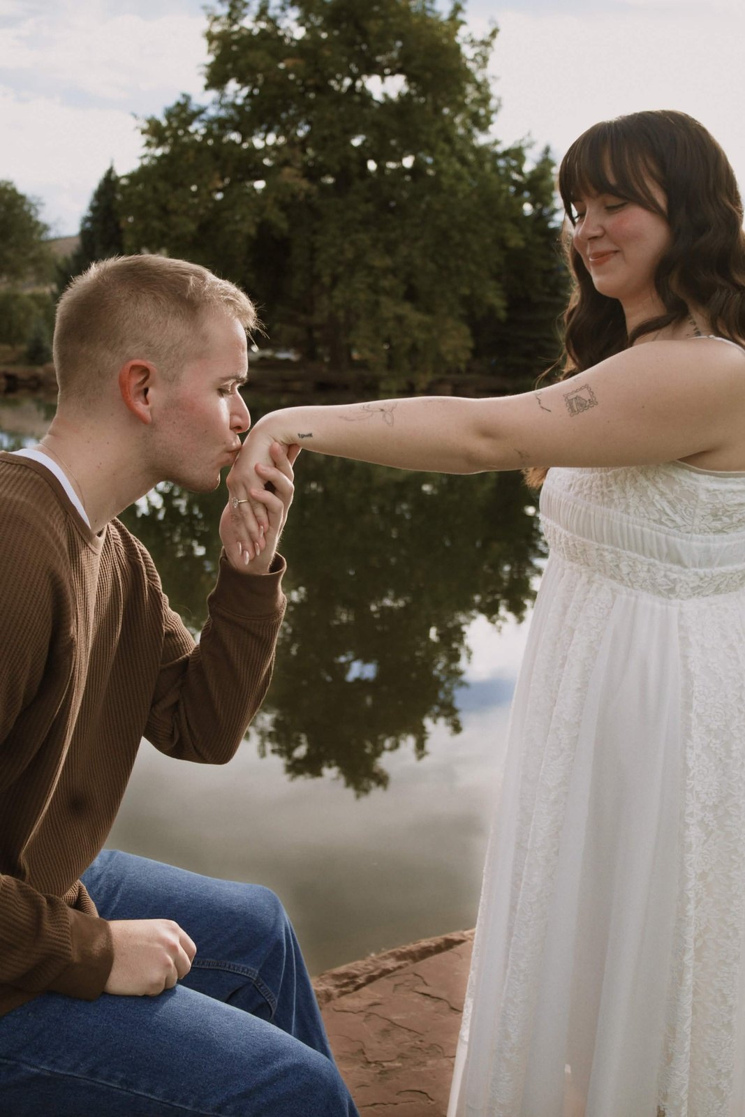 Groom kissing her hand by the water