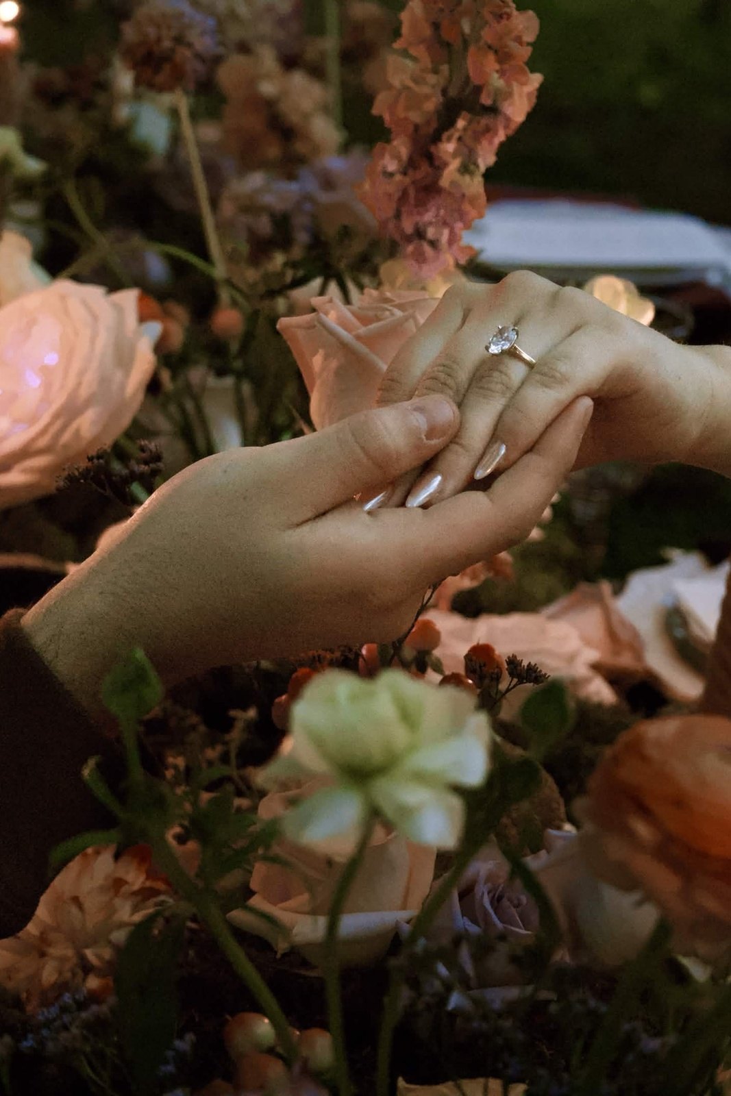 Engagement ring over a candlelit floral table