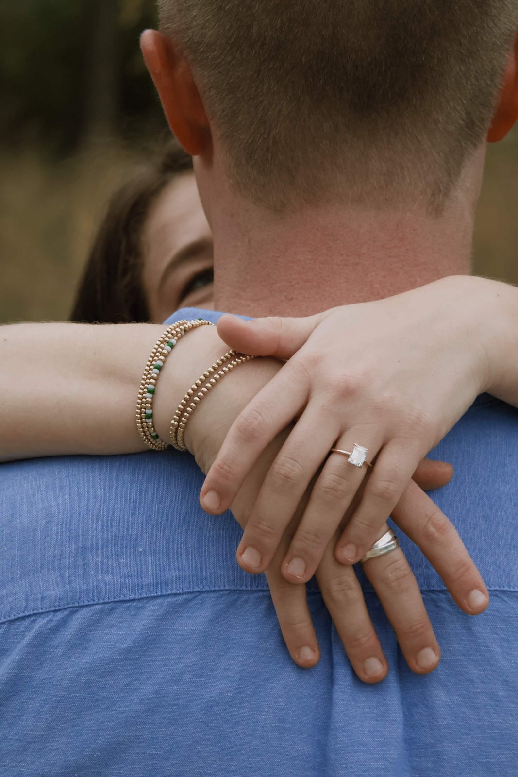 Engagement ring as she hugs him from behind