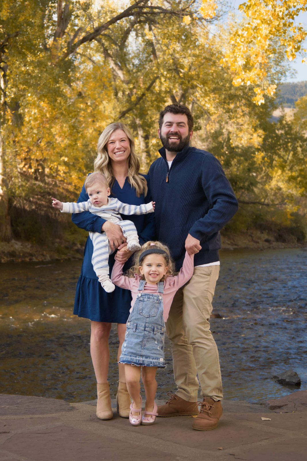 Family with two little kids by the river in fall