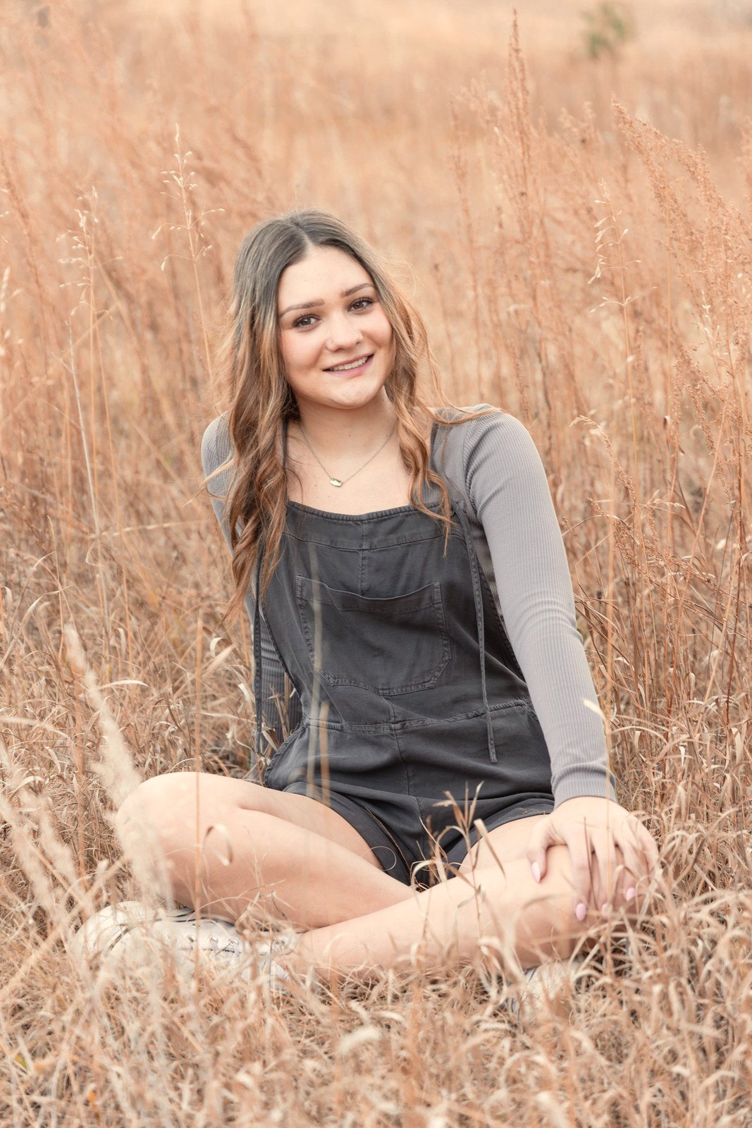 Senior portrait in golden grass at sunset