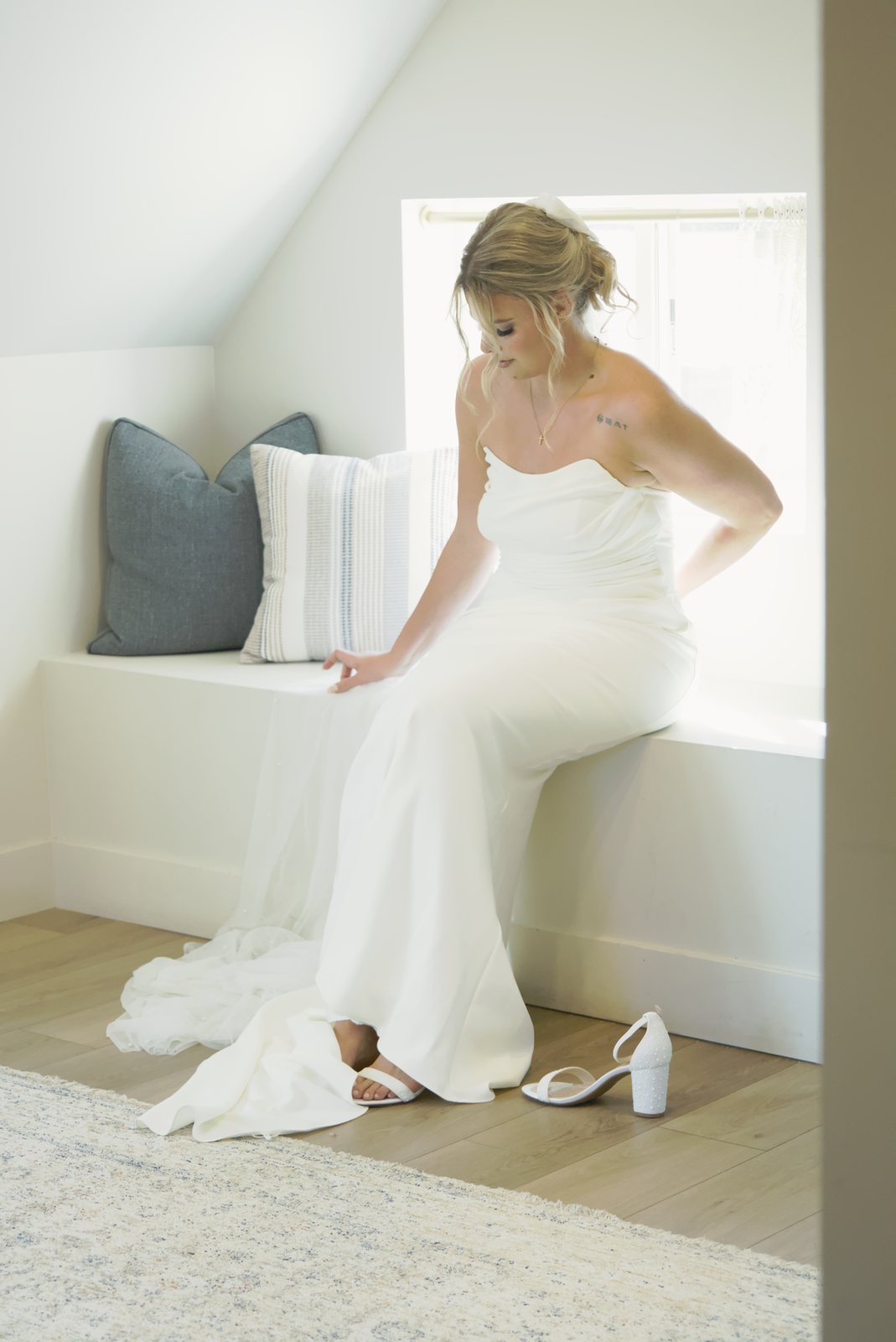 Bride putting on her shoes by a sunny window