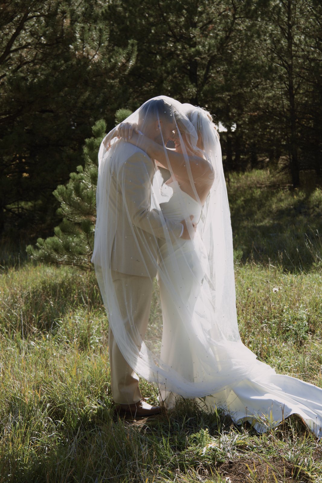 Couple wrapped in the veil in the pines