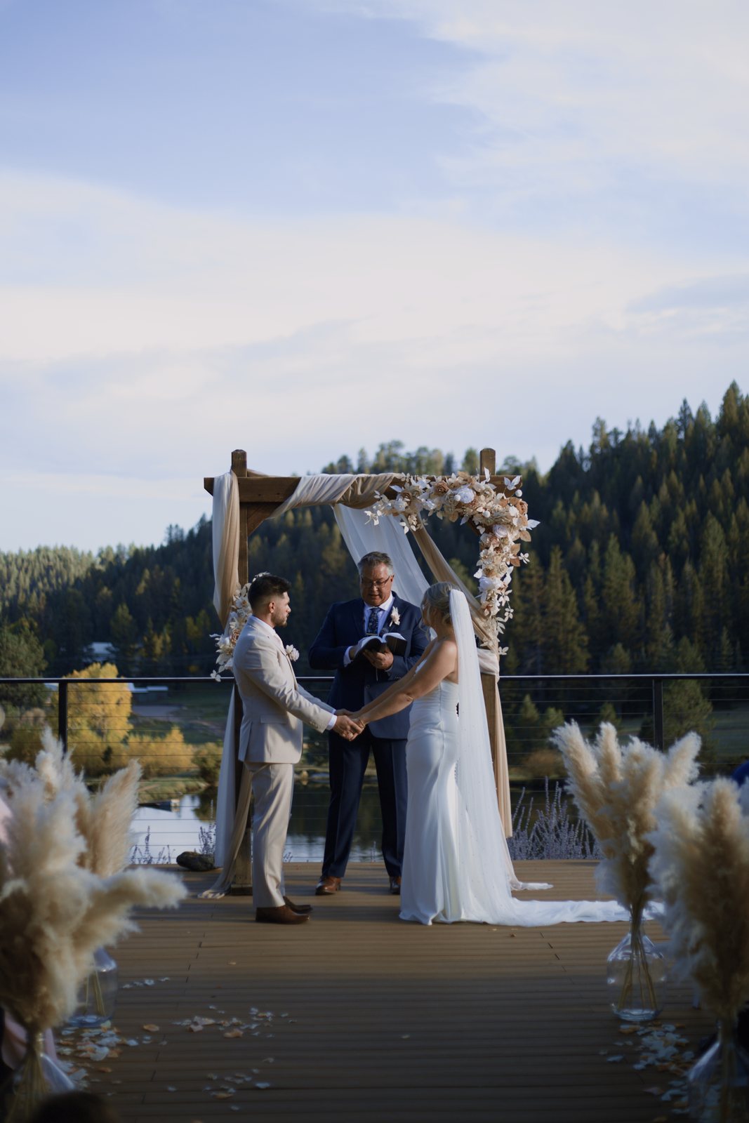 Ceremony under a floral arch with forest behind