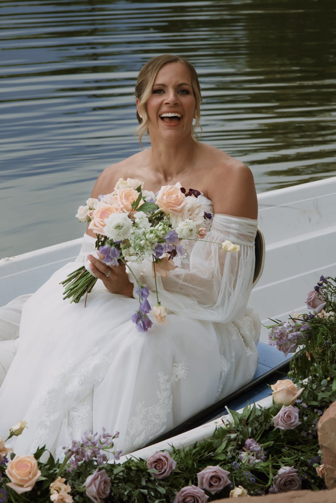 Bride laughing in a flower-filled rowboat