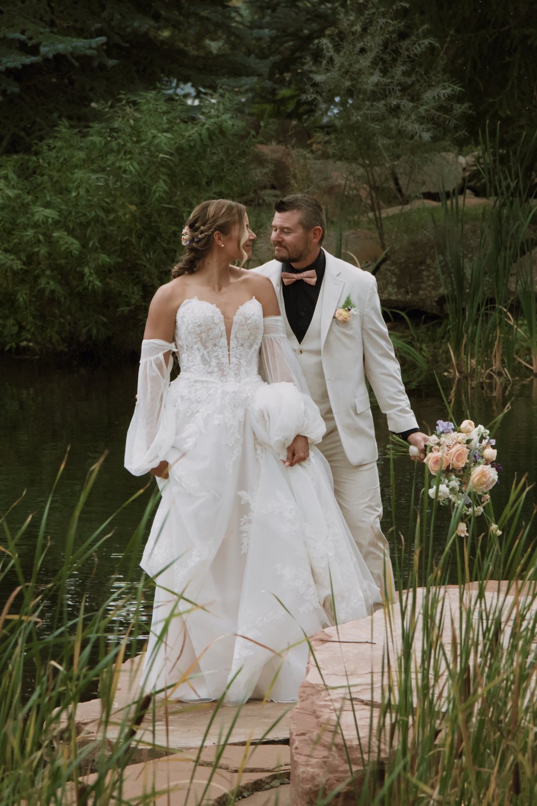 Couple walking across stepping stones by a pond