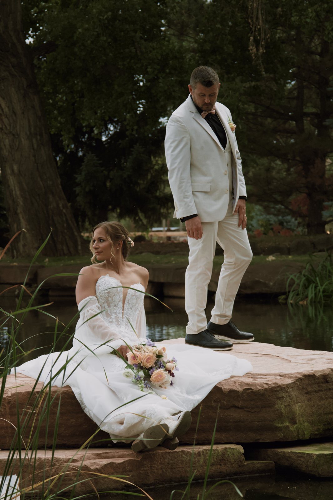 Bride sitting on a rock by the pond