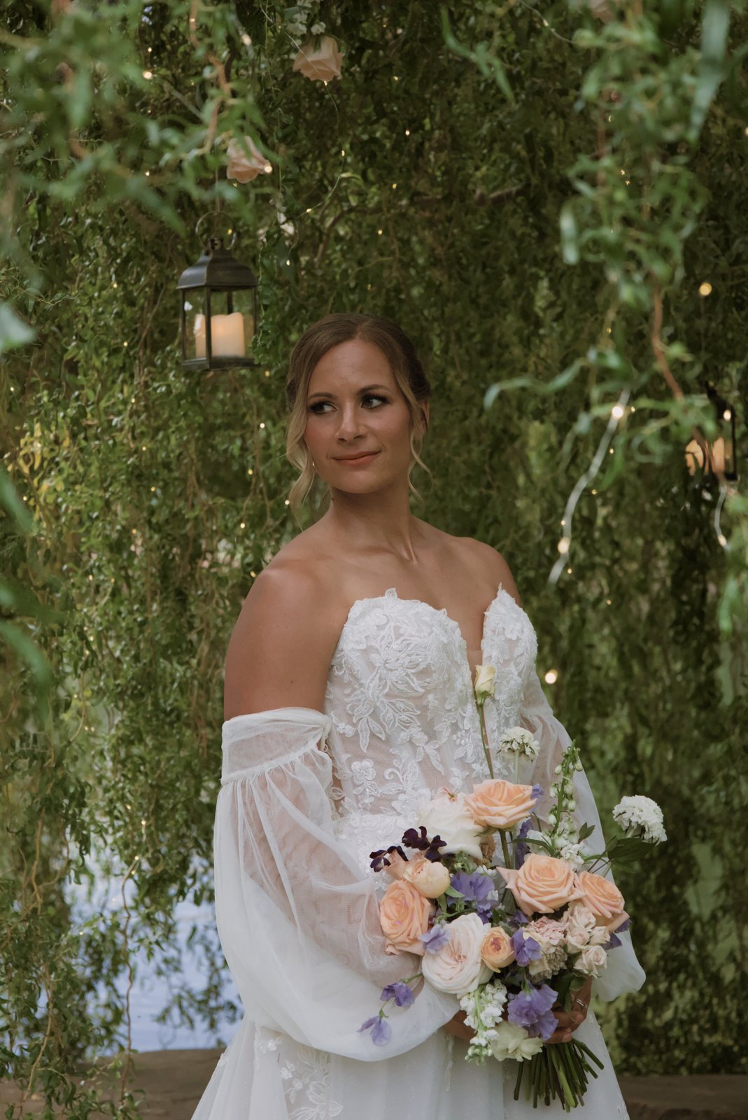 Bride holding her bouquet under willow trees